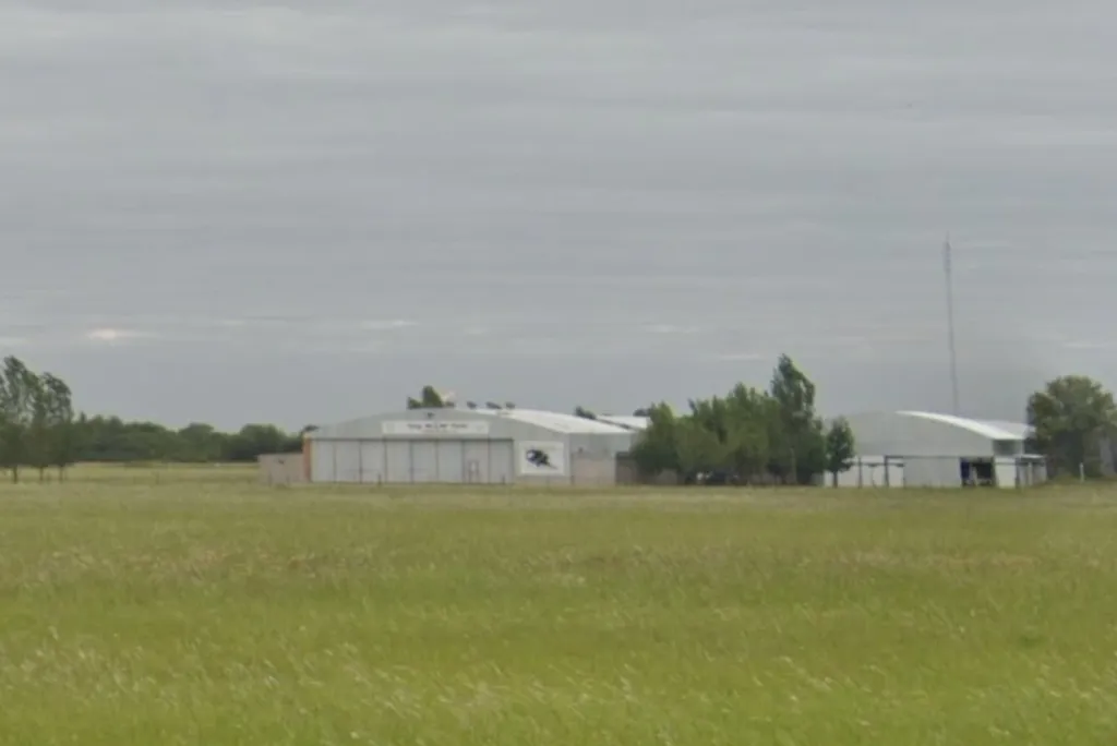 Coronel Olmedo airfield, with several hangars and a large field in front of them.