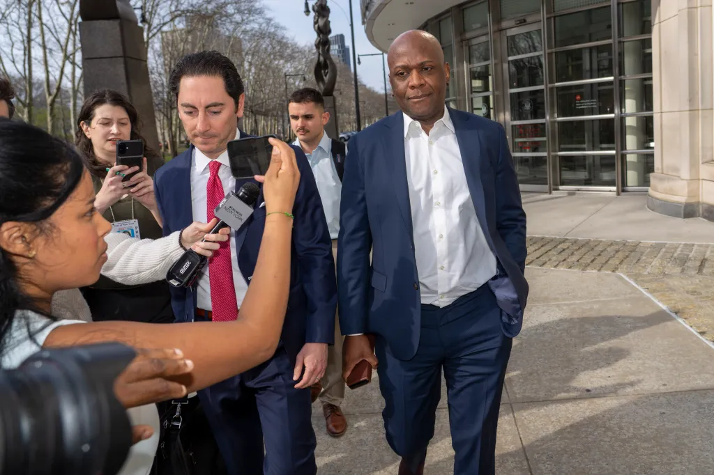 Roberto Samedy leaving federal court with his lawyer, surrounded by reporters.