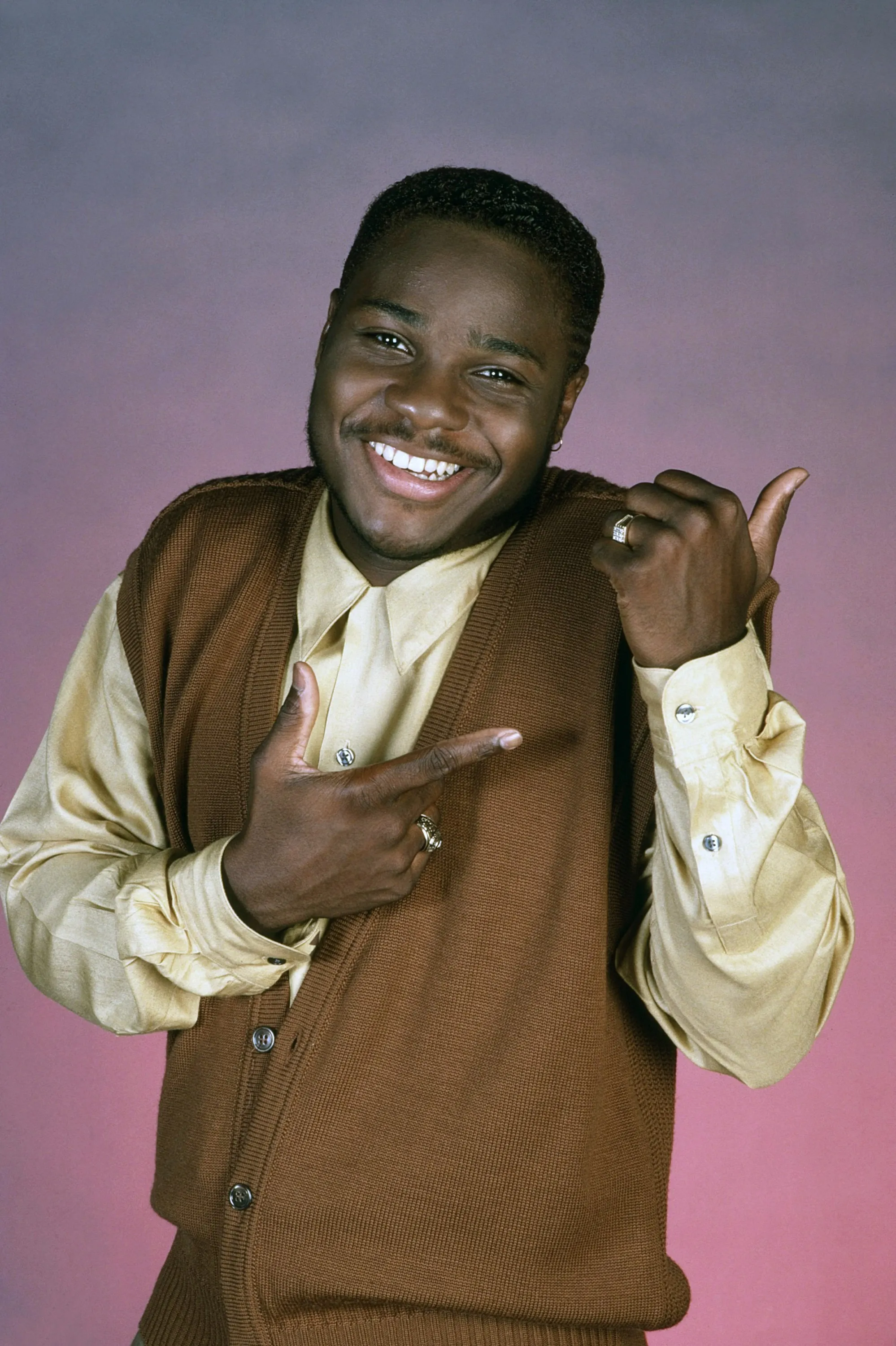 Malcolm-Jamal Warner in a promotional photo for The Cosby Show, smiling and gesturing.