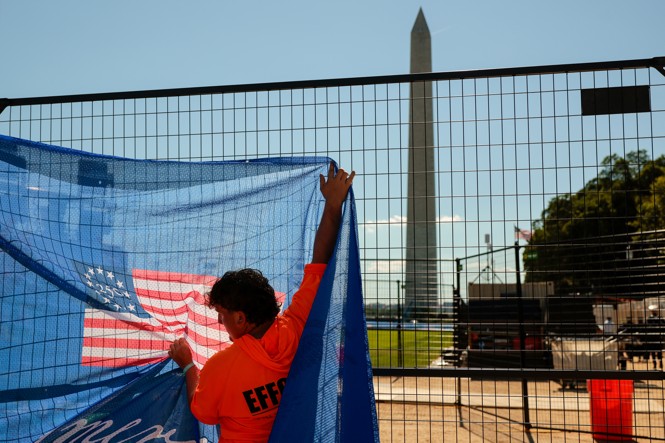 A person hanging flag on a fence