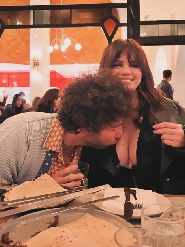 Benny Blanco kissing Selena Gomez's chest in a restaurant.