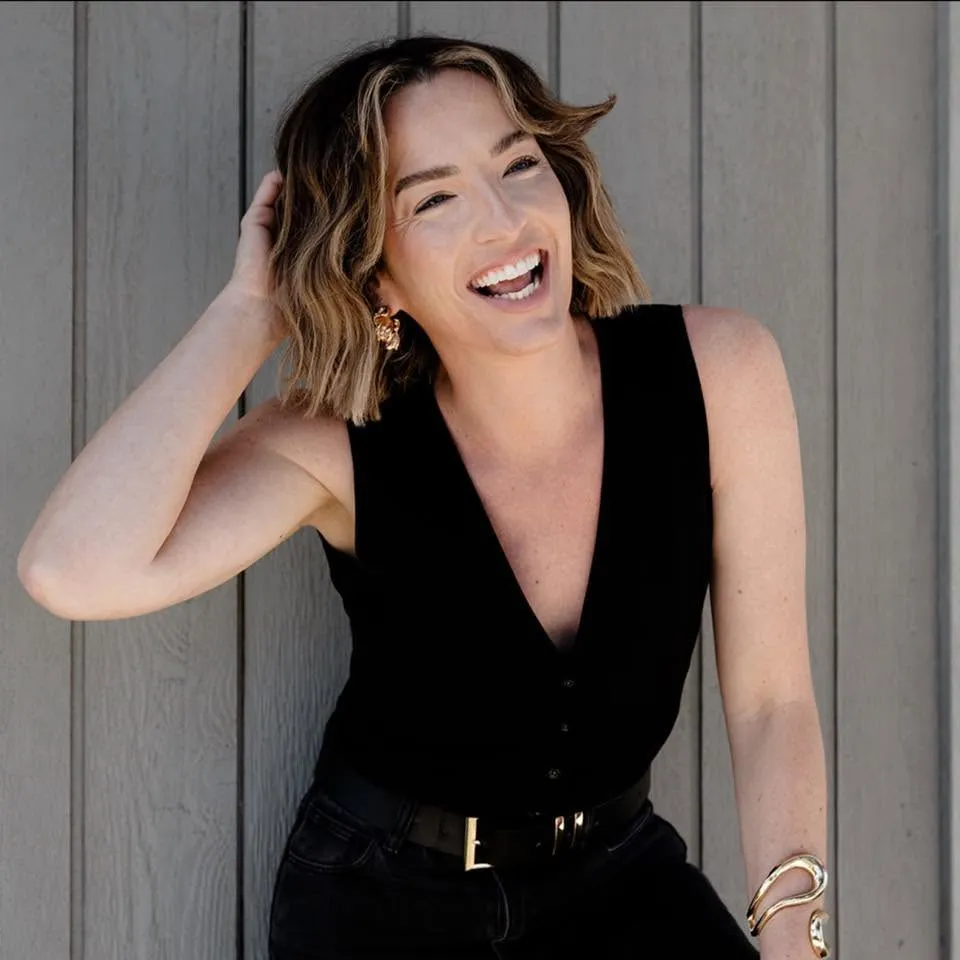 Doctor Nici Sweaney, CEO of AI Her Way, laughing while holding her hair.