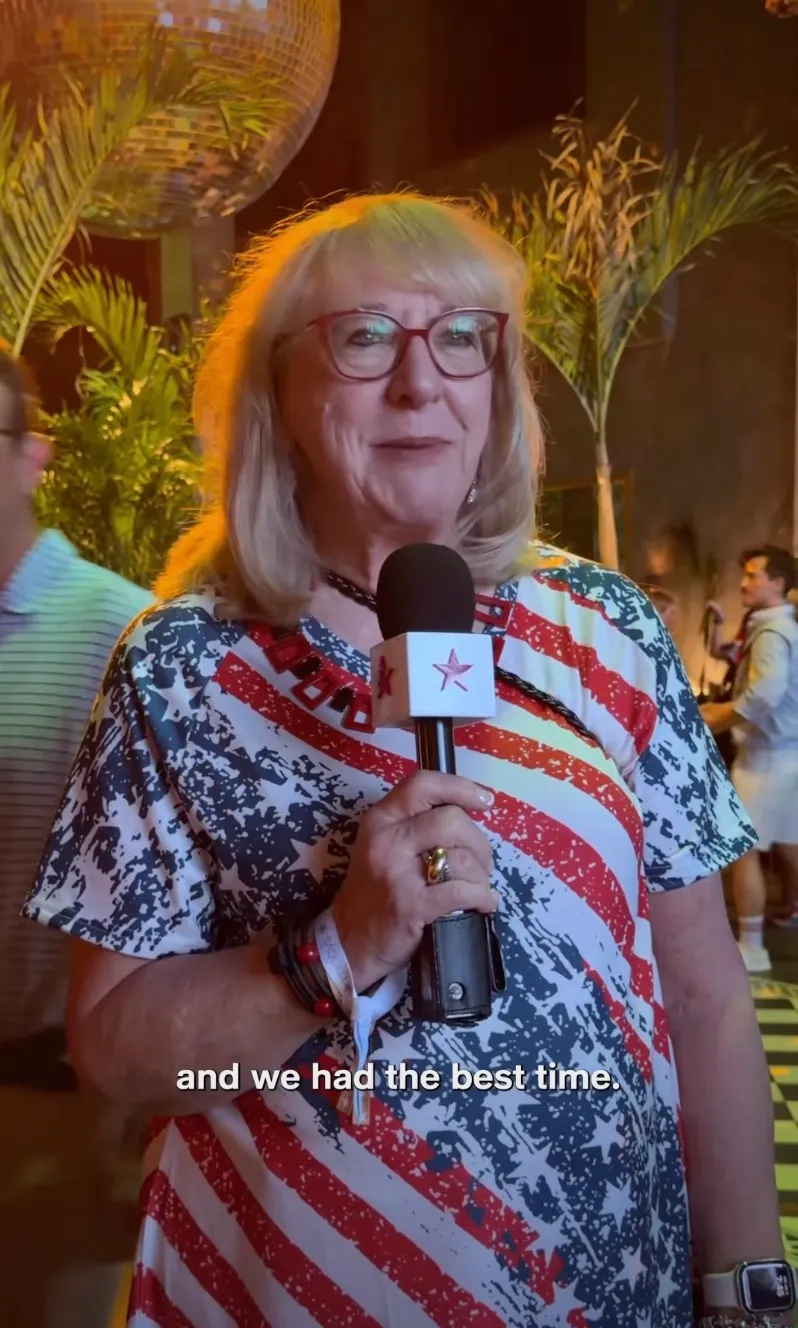Donna Kelce speaks into a microphone, wearing a red, white, and blue American flag print dress.