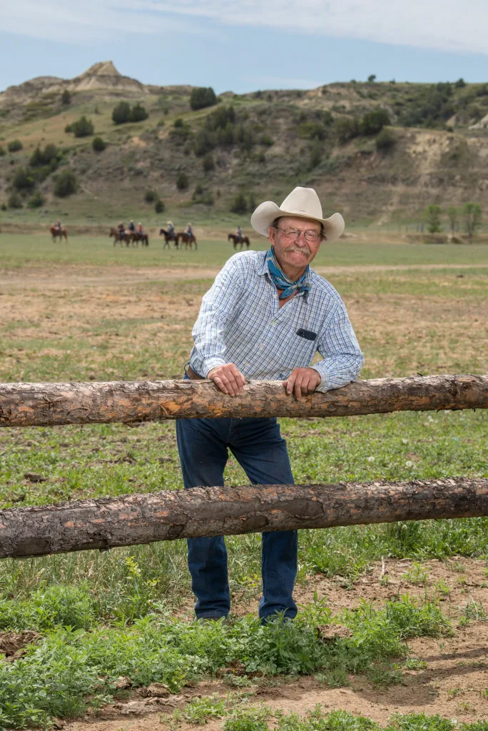 Doug Tescher, owner of a ranch near the Teddy Roosevelt Presidential Library in Medora, North Dakota, smiles while leaning on a wooden fence.