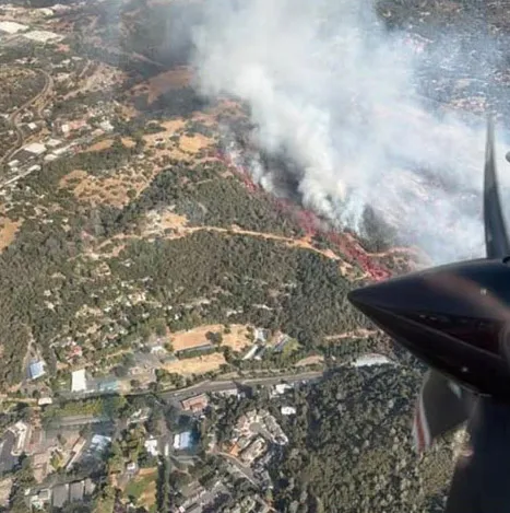 Aerial view from an aircraft showing the Dove Fire with red fire retardant visible.