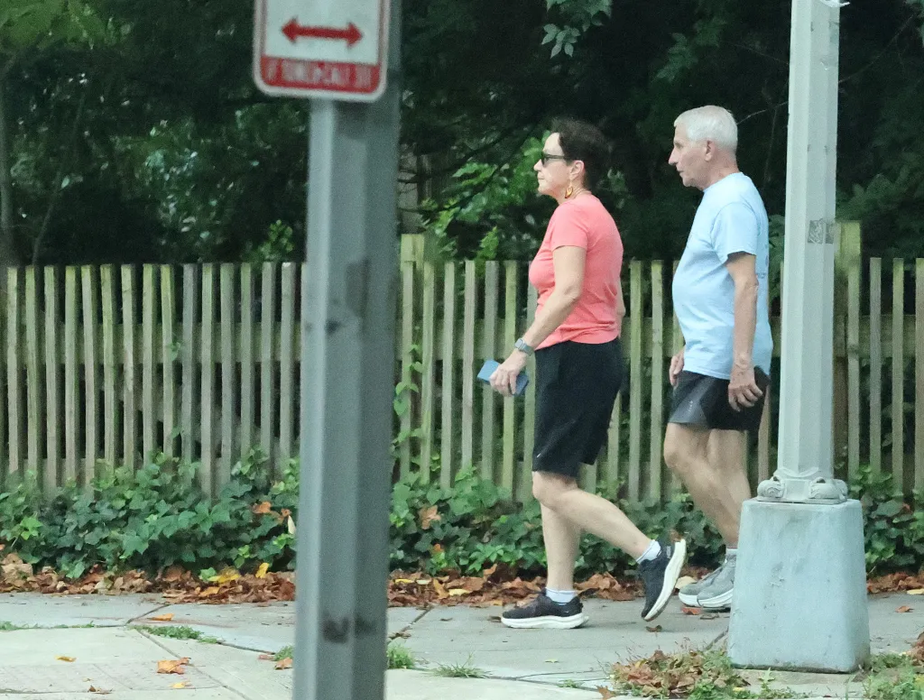Dr. Anthony Fauci and Christine Grady walk outdoors.