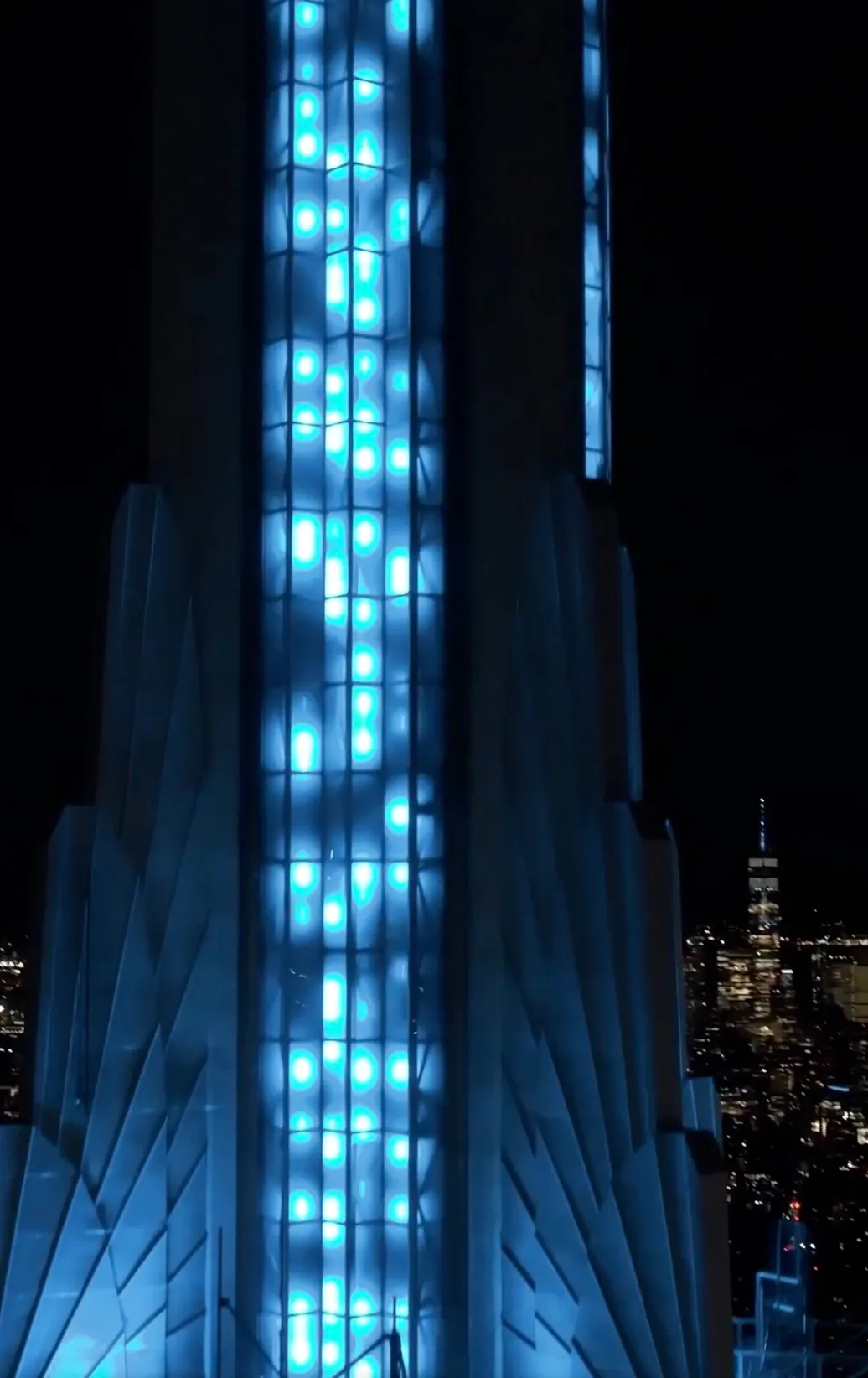 The Empire State Building illuminated in blue light at night.