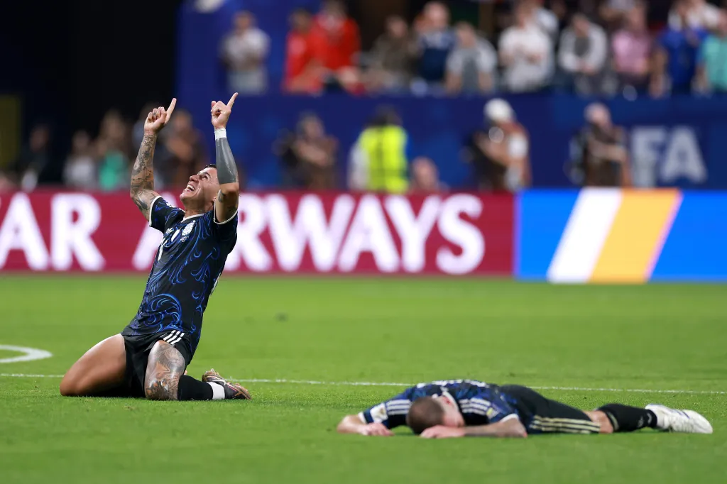 Enzo Fernandez celebrates on his knees while another player lies on the field after Argentina's win over England in the FIFA World Cup 2026 Semi Final.
