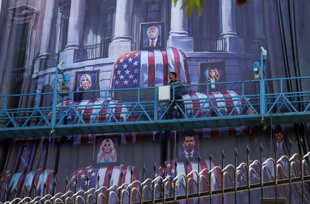 An Iranian worker adjusts an anti-US billboard featuring pictures of US President Donald Trump and his family on top of US flag-draped coffins, in Tehran, Iran.