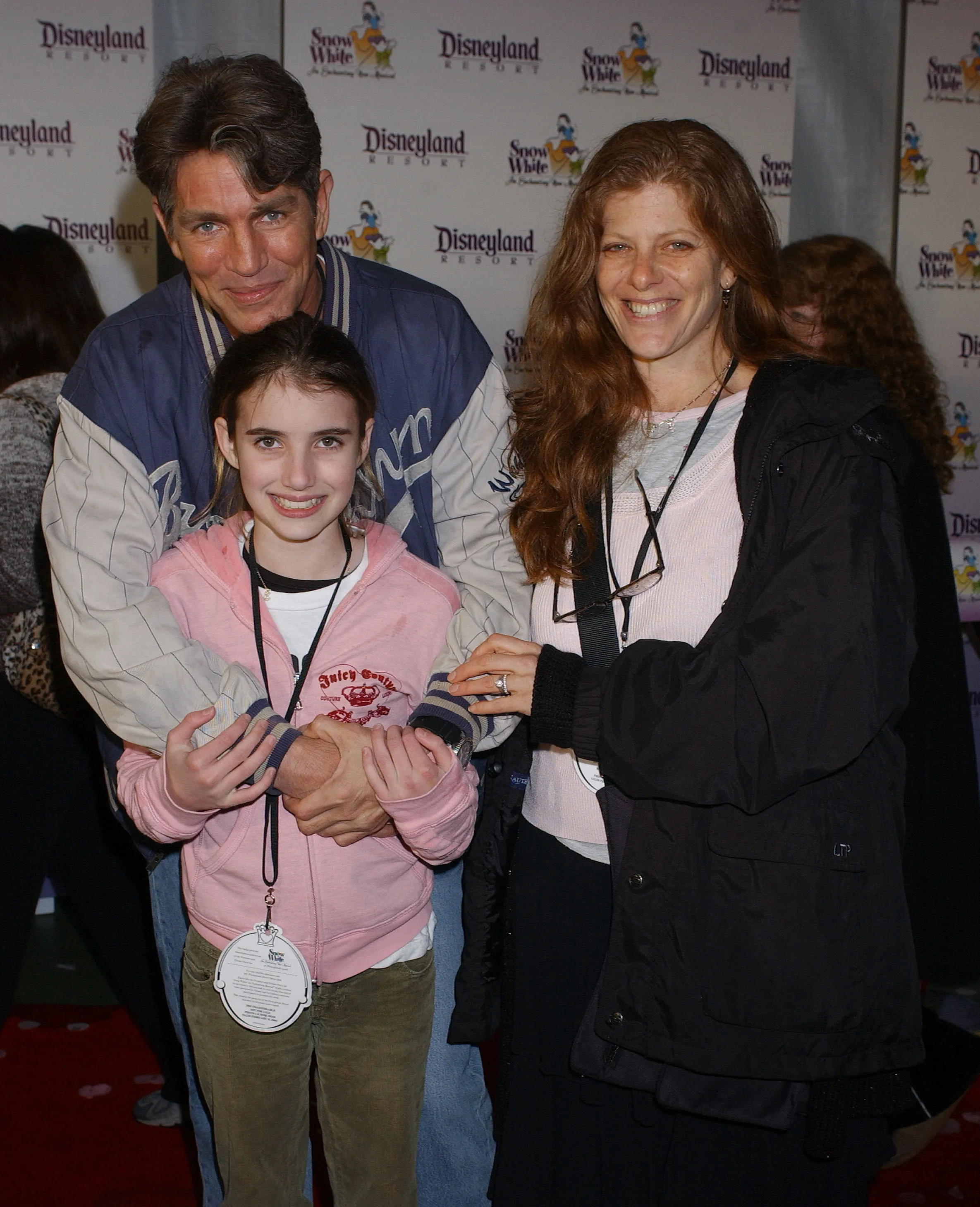 Eric Roberts, daughter Emma, and wife Eliza smiling at the premiere of "Snow White - An Enchanting New Musical" at Disneyland.