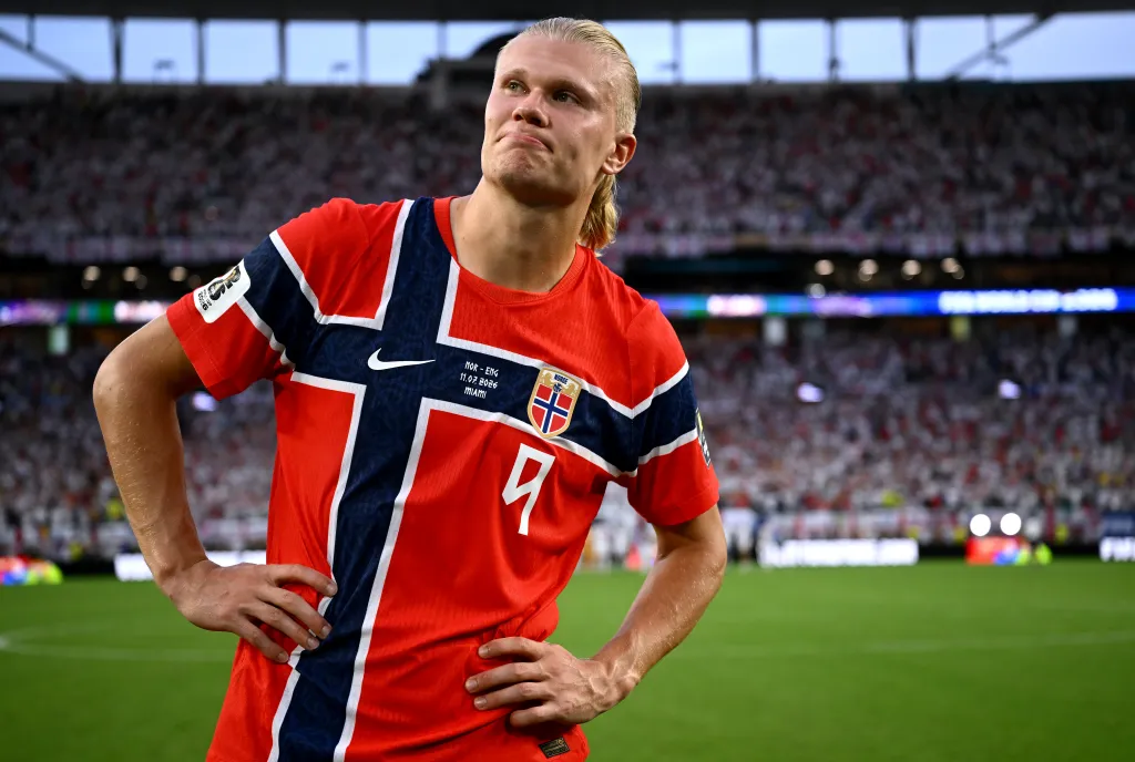 Erling Haaland wearing his Norway jersey and standing on a soccer field after a loss.