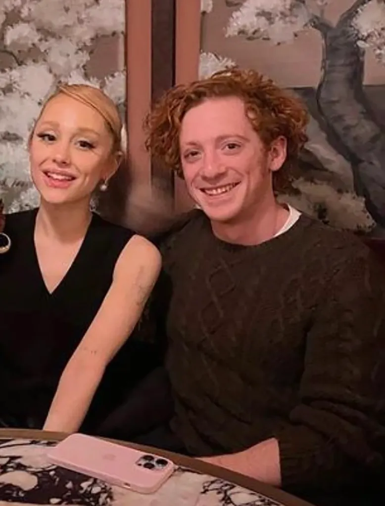 Ethan Slater and Ariana Grande smiling at the camera.