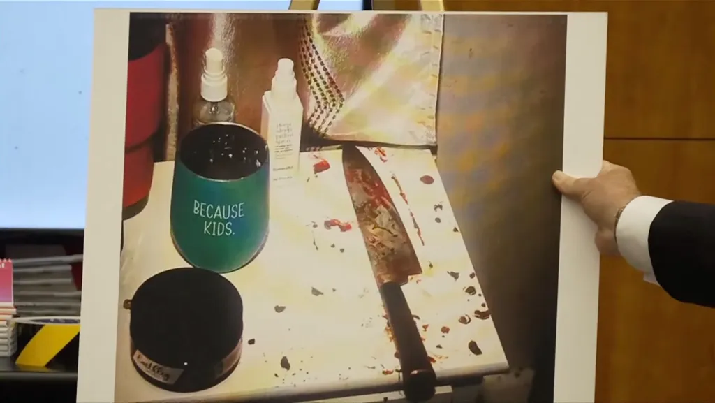 Crime scene photo showing a bloodied kitchen knife next to a cup emblazoned with the message, "Because kids."