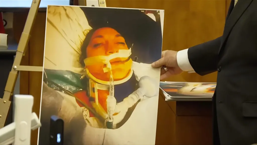 Crime scene photo of Lindsay Clancy in a hospital bed with a cervical collar and tubes in her mouth.
