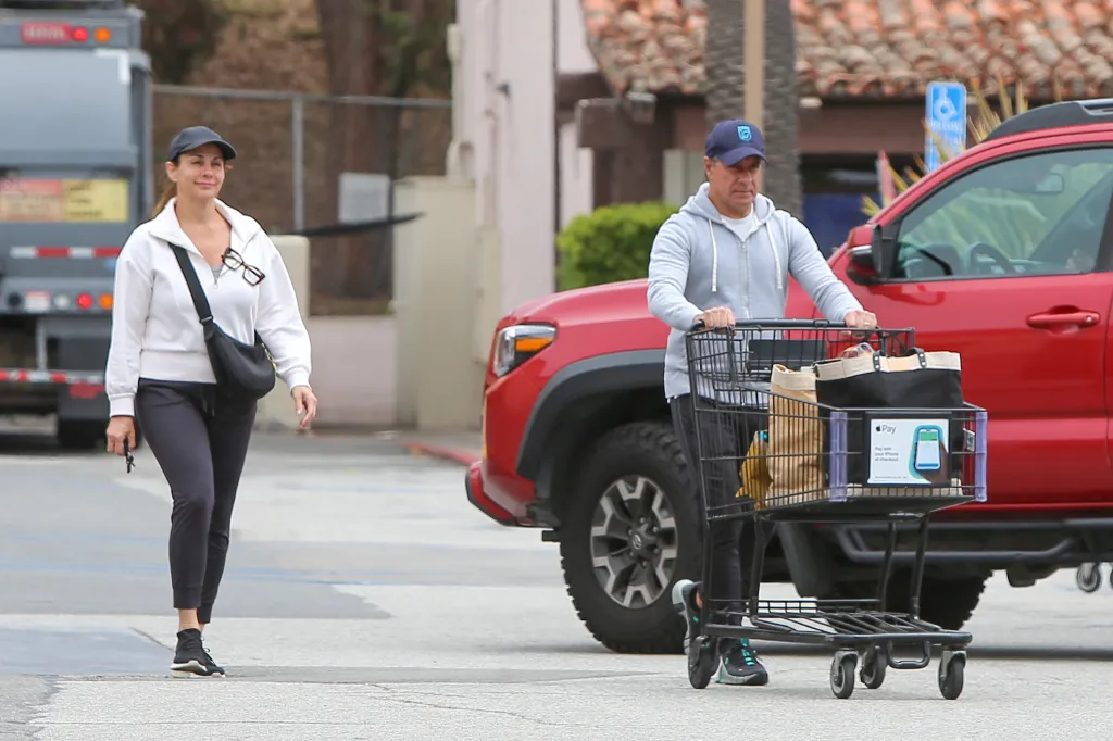 Alberto Carvalho pushes a grocery cart while his wife walks beside him.