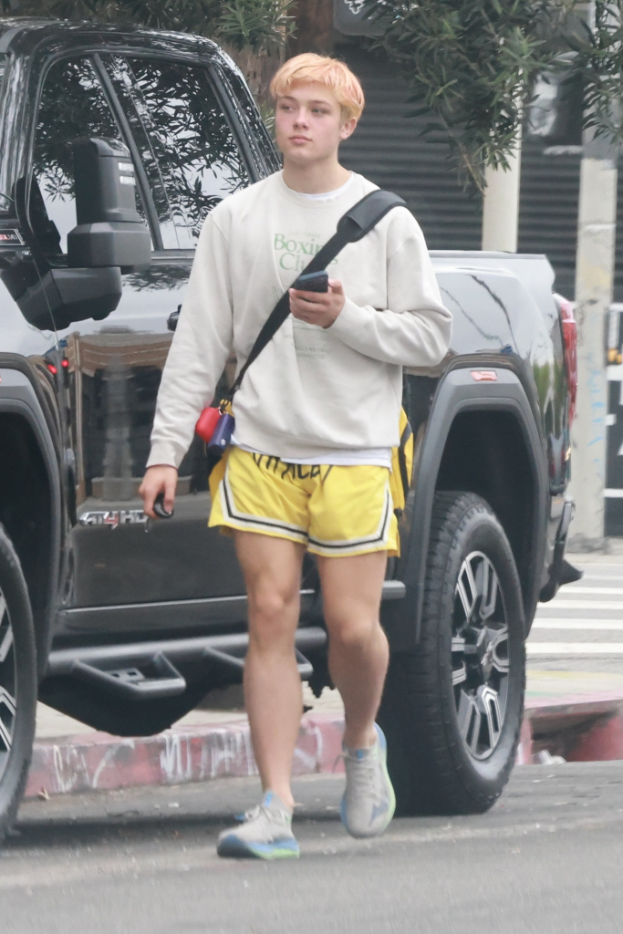 Knox Leon Jolie-Pitt leaving a Muay Thai class, wearing a white hoodie, yellow shorts, and carrying a yellow gym bag.
