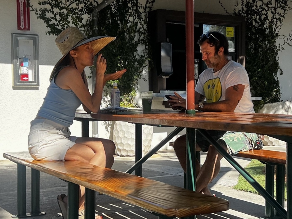 Bijou Phillips and Jamie Mazur seated at an outdoor picnic table.