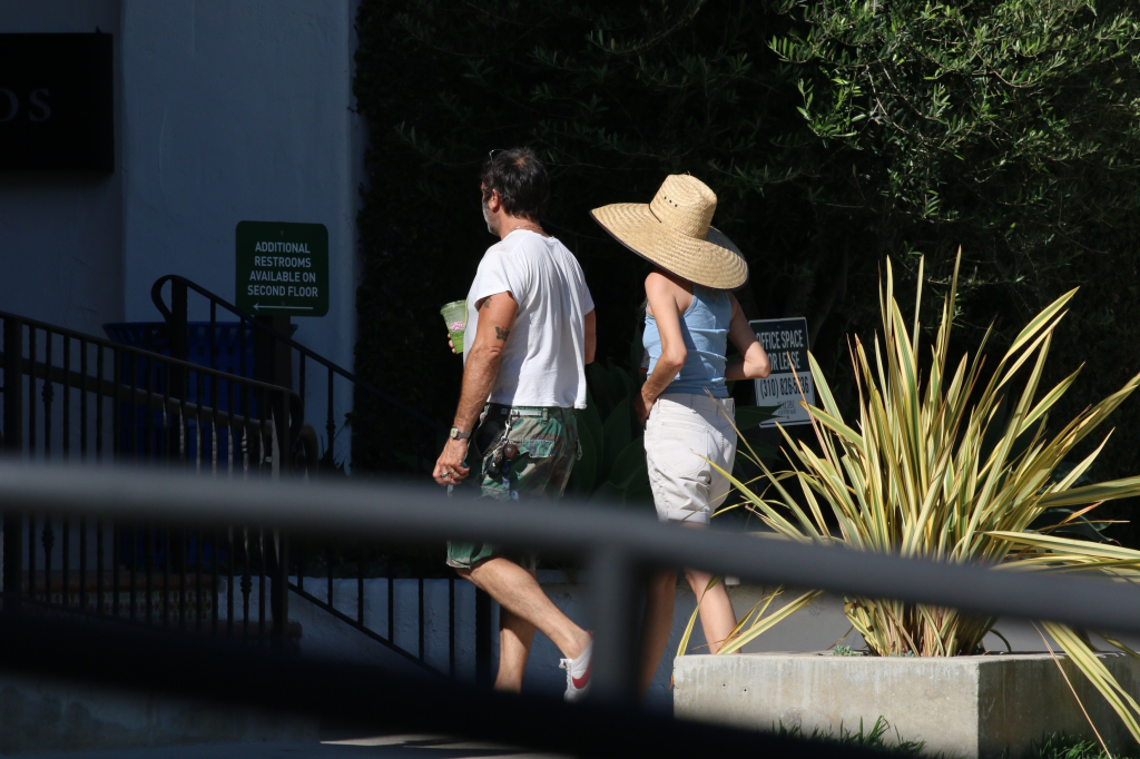 Bijou Phillips wearing a straw hat and Jamie Mazur walking together outdoors.