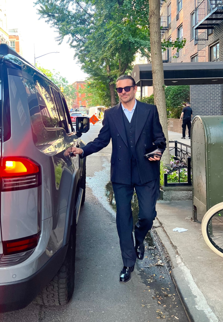 Bradley Cooper smiling while opening a car door.