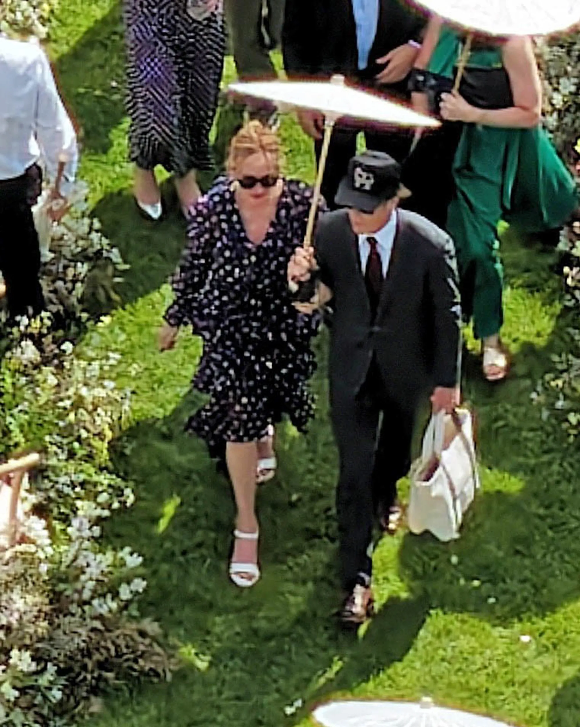 Julia Roberts and Daniel Moder walking outdoors, with Moder holding an umbrella over Roberts.
