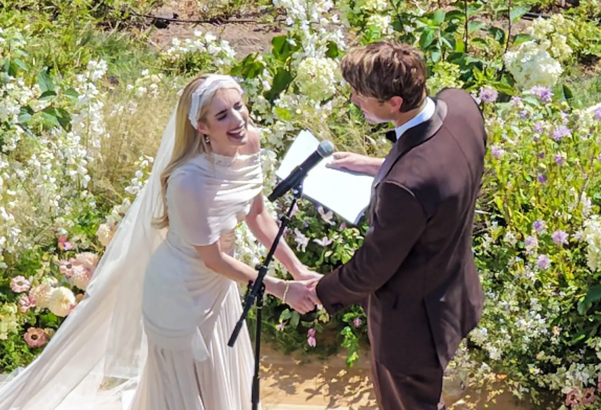 Emma Roberts and Cody John holding hands during their wedding ceremony.