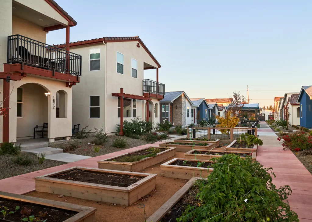 Exterior of single-family residential neighborhood in Chico, California, featuring houses with balconies and community garden beds.