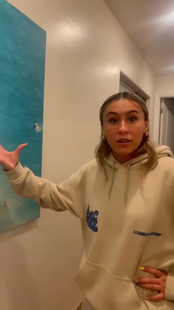 A woman gesturing towards a photo of her family hanging in an Airbnb.