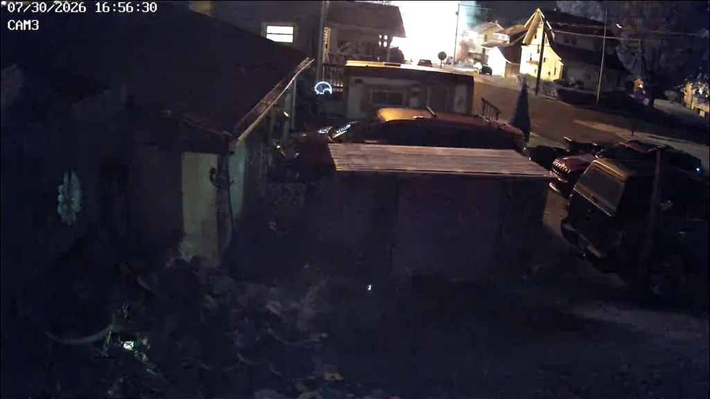 Night vision video of a house exploding in a neighborhood.