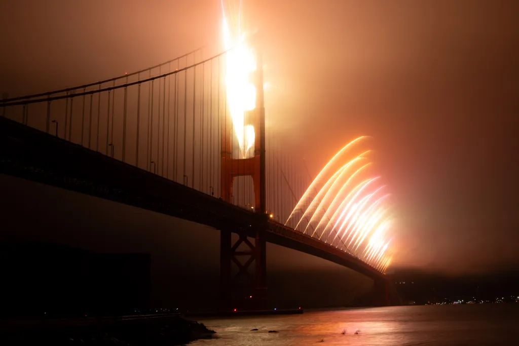 Fireworks illuminate the Golden Gate Bridge at night.