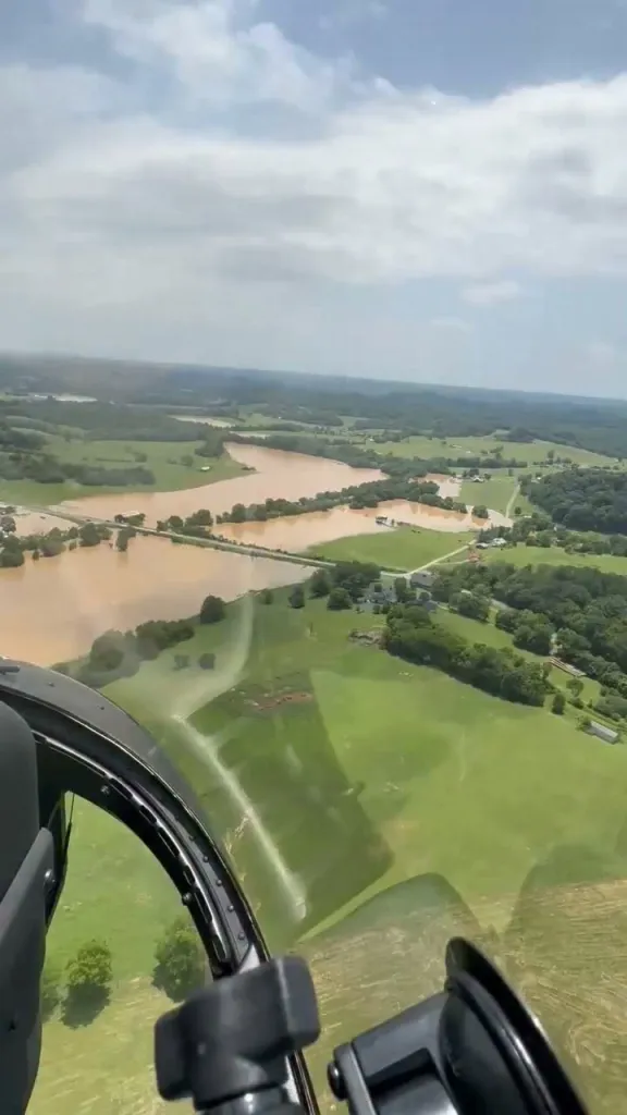 Aerial view from a helicopter showing flooded farmland and houses.