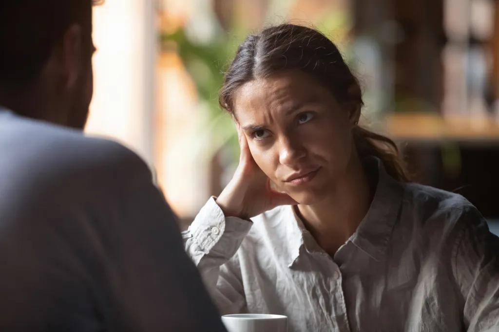 A bored woman with her hand on her cheek looks annoyed during a speed dating event.