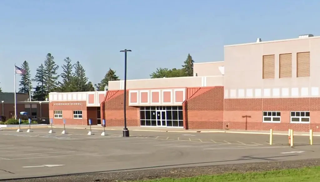 Underwood School building exterior, with an American flag and a parking lot.