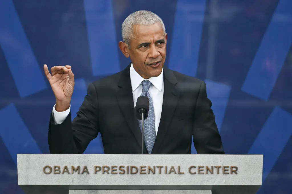 Former US President Barack Obama speaking at a podium with "Obama Presidential Center" written on it.