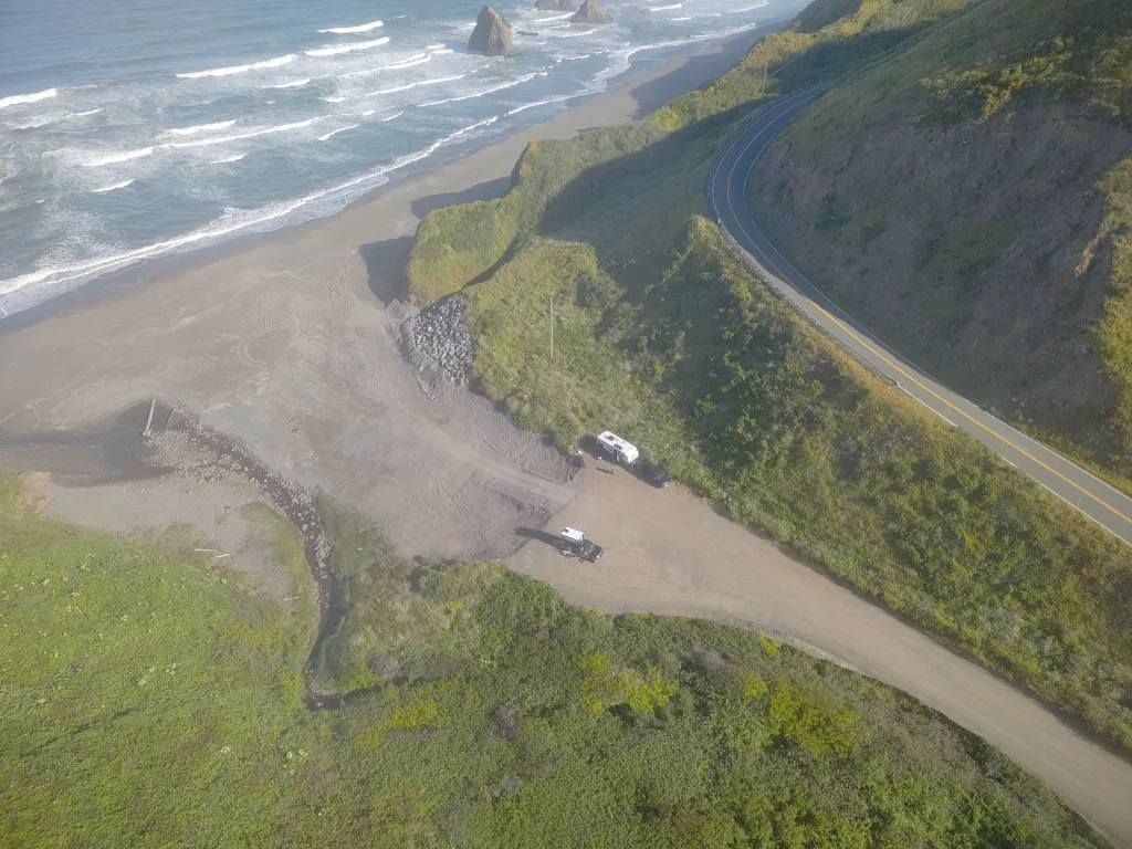 Aerial view of the California coast with a highway and beach, where 136 acres of land were transferred to local Native American tribes.