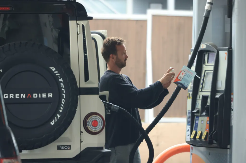 A man at a gas station in Los Angeles, California, holding a credit card as he prepares to pay at the pump.
