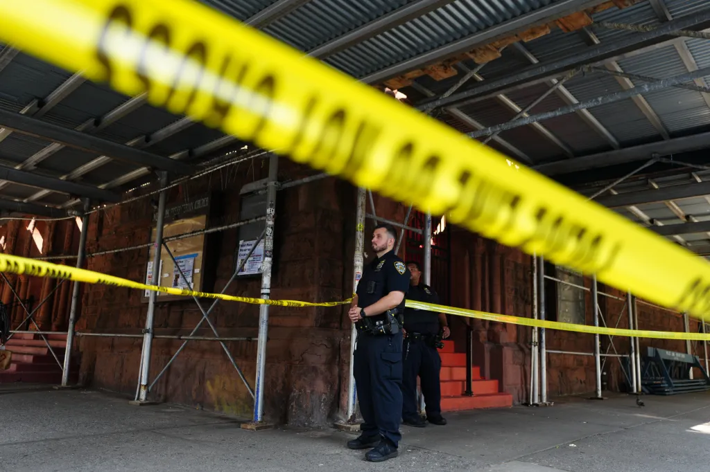 Police officers standing behind crime scene tape at the site of a double stabbing on the Upper West Side of Manhattan.