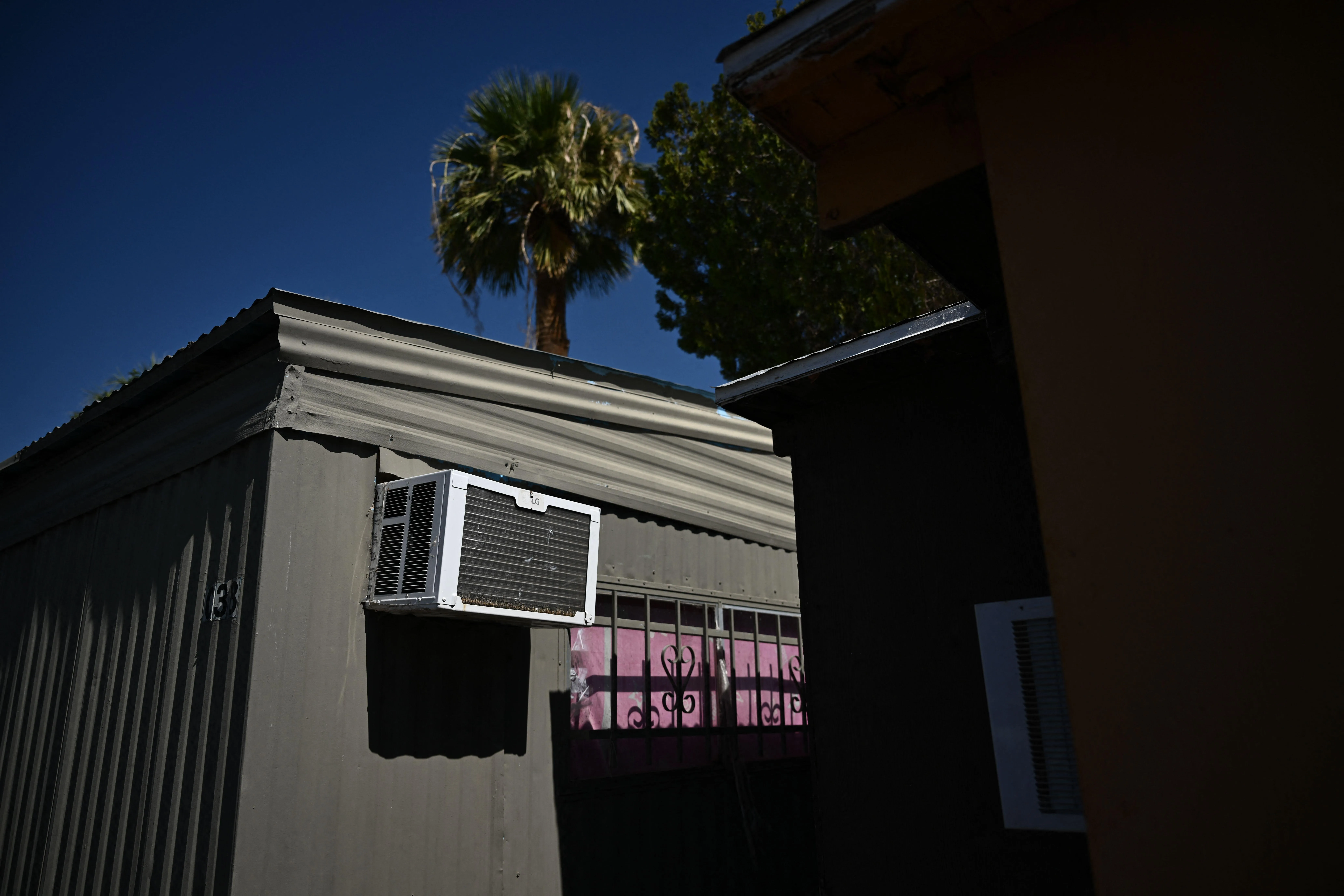 A window mounted air conditioning unit hangs outside a mobile home during a record heat wave in Phoenix