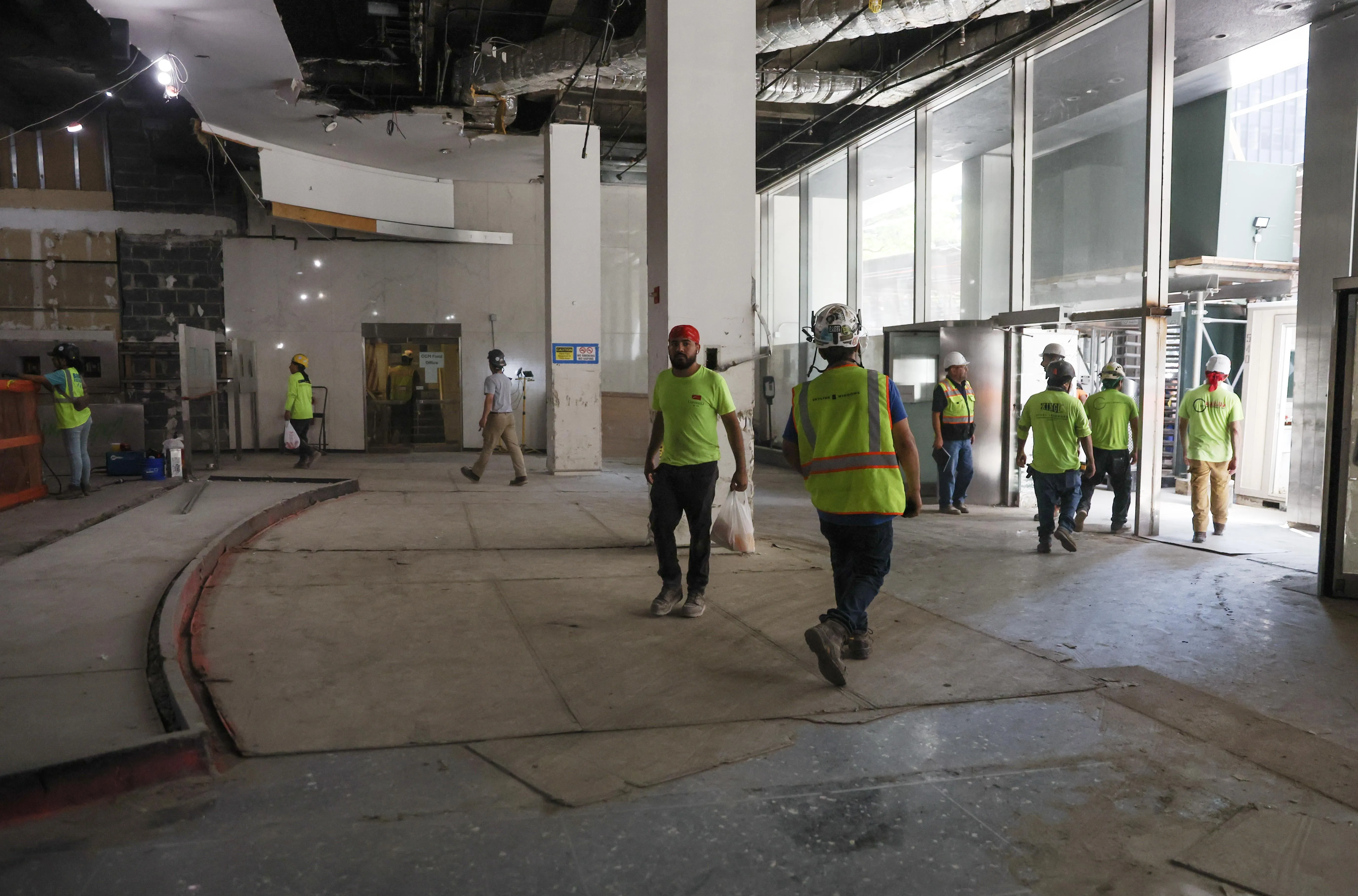 Workers in bright green vests walking in lobby of building under construction