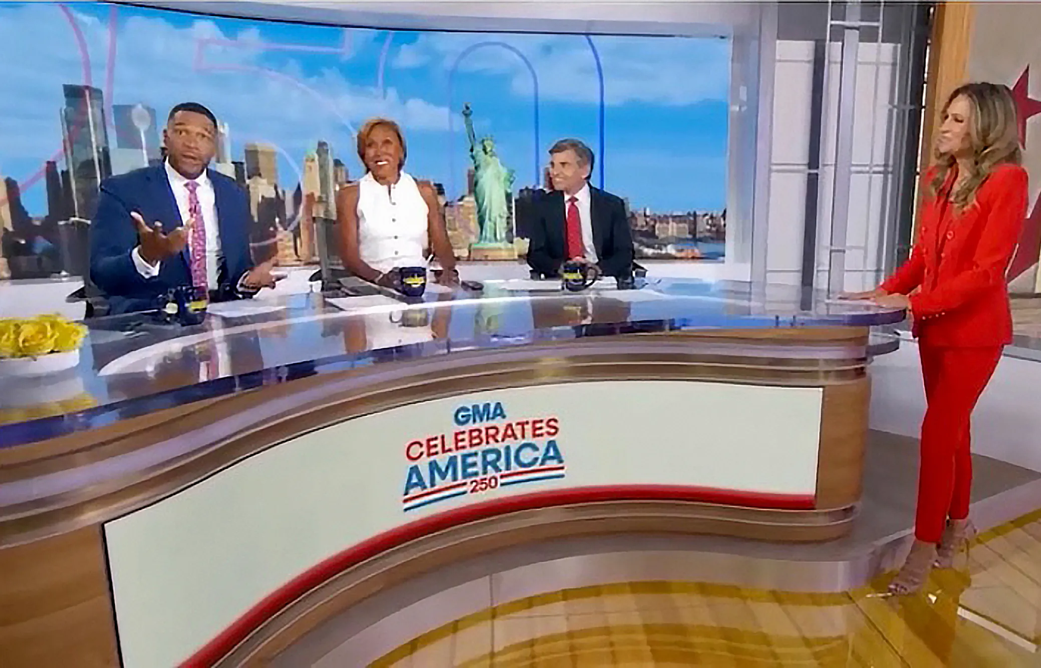 Good Morning America co-hosts Robin Roberts, Michael Strahan, George Stephanopoulos, and an unknown woman in red, discussing an "intimate" wedding.
