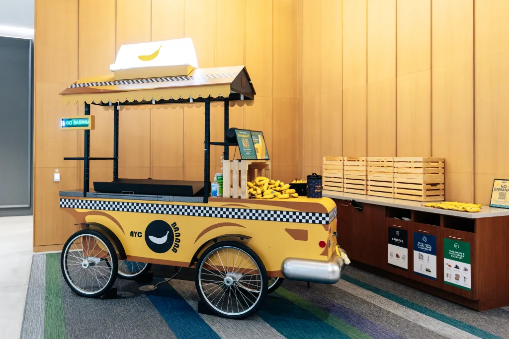 A banana stand designed like a yellow NYC taxi cab, with a digital "GO BANANA" sign.