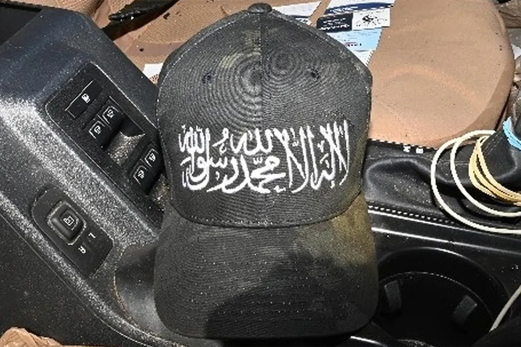 A black baseball cap with white Arabic script on the front, resting in a car's interior.