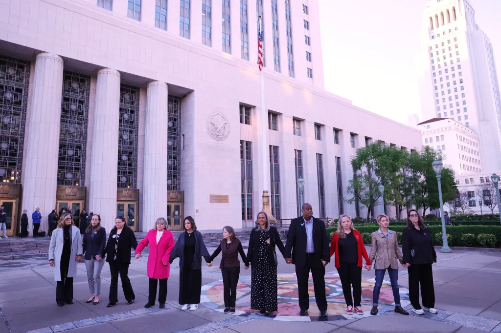 A group of individuals holding hands outside a United States courthouse.