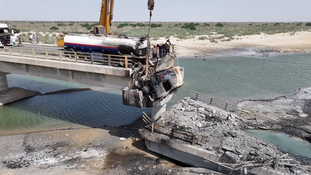 Workers clean up wreckage around a damaged bridge, following US airstrikes in Hormozgan Province, Iran.