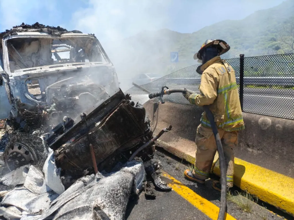 A firefighter works to douse the smoking engine of a destroyed vehicle after a devastating highway collision in Jalisco, Mexico, on Sunday.