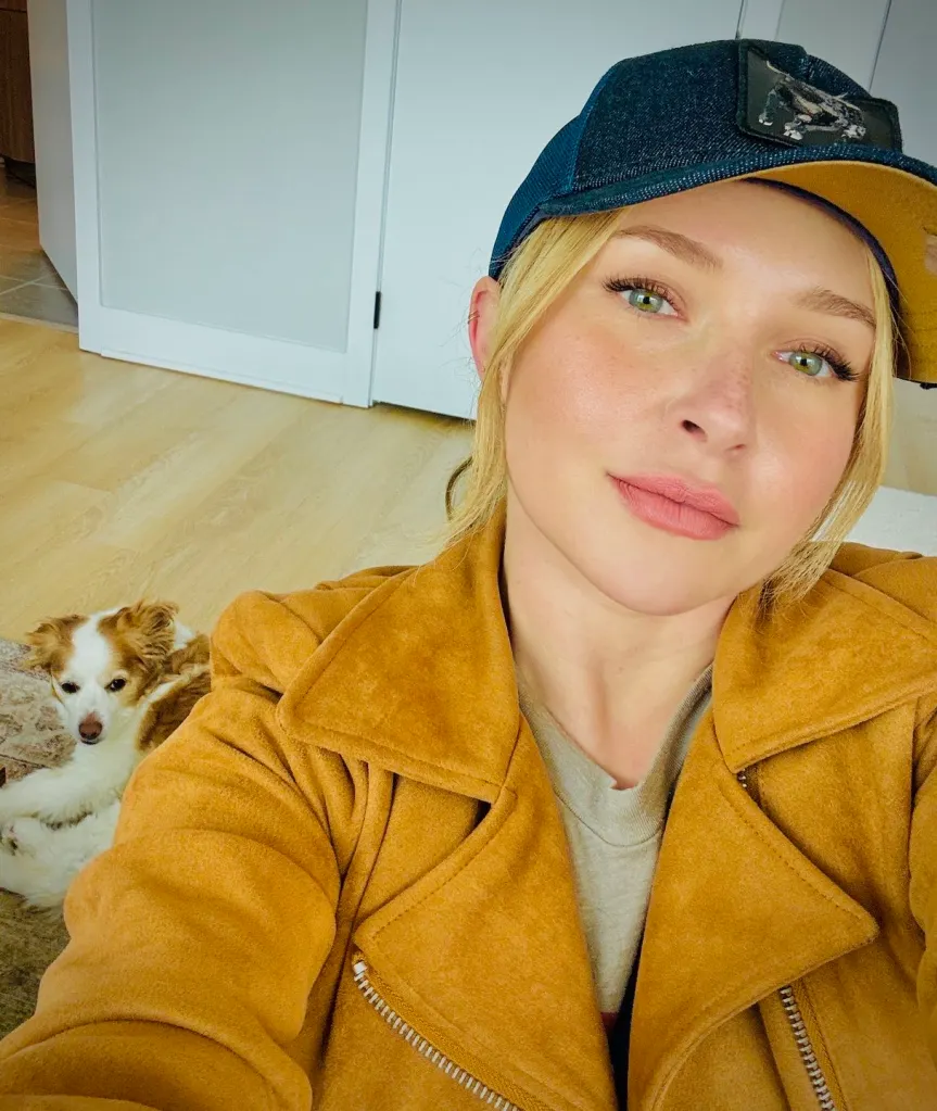 Hayden Panettiere wearing a brown jacket and a hat, taking a selfie with her dog.