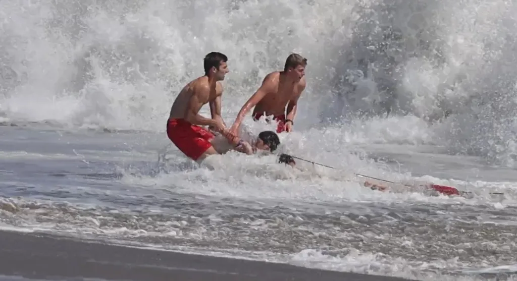 Two lifeguards rescue a young boy from large waves.