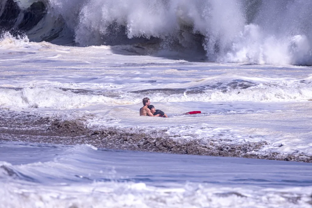 A lifeguard rescuing a child from large waves at Santa Cruz.