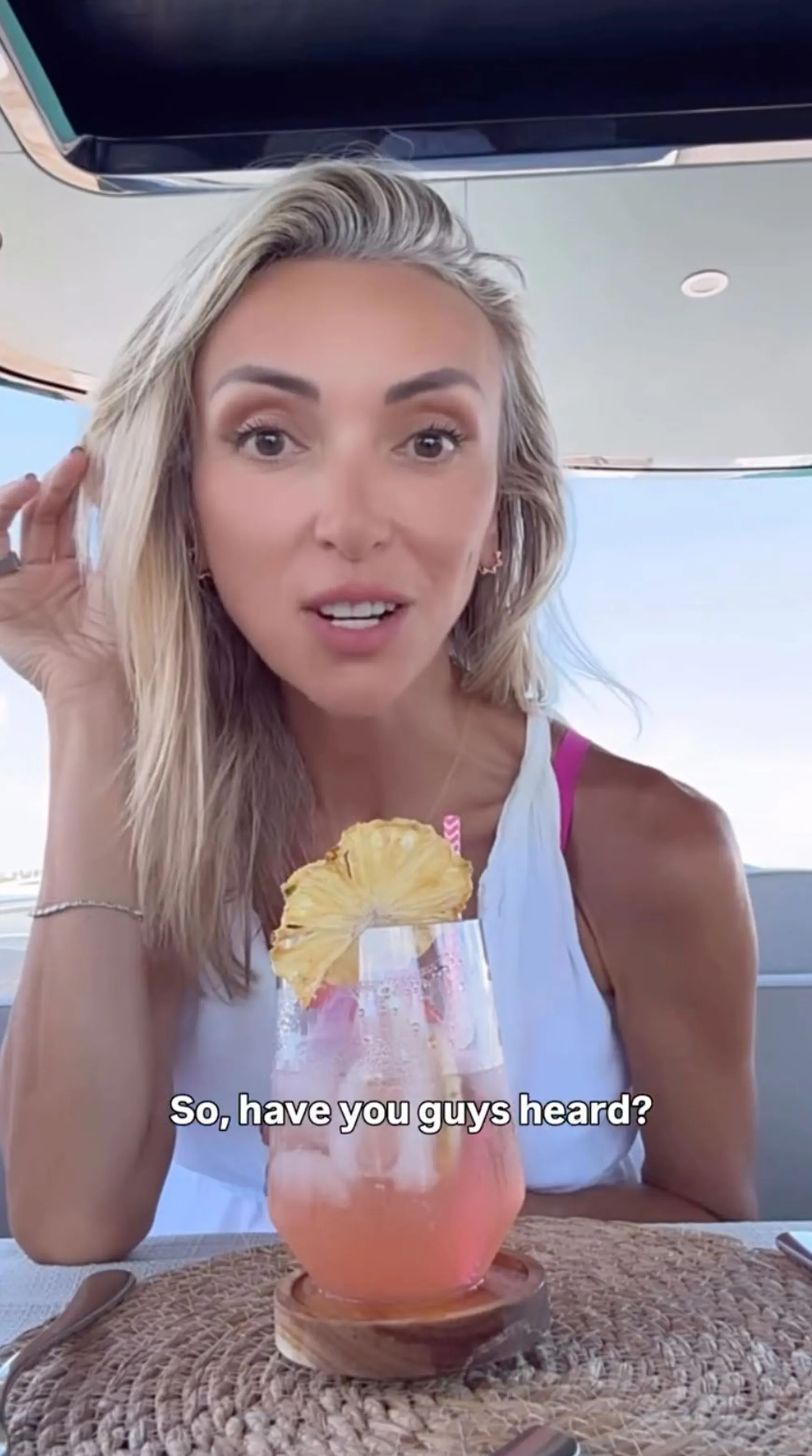 Giuliana Rancic on a boat holding a pink drink with pineapple on top and the text "So, have you guys heard?"