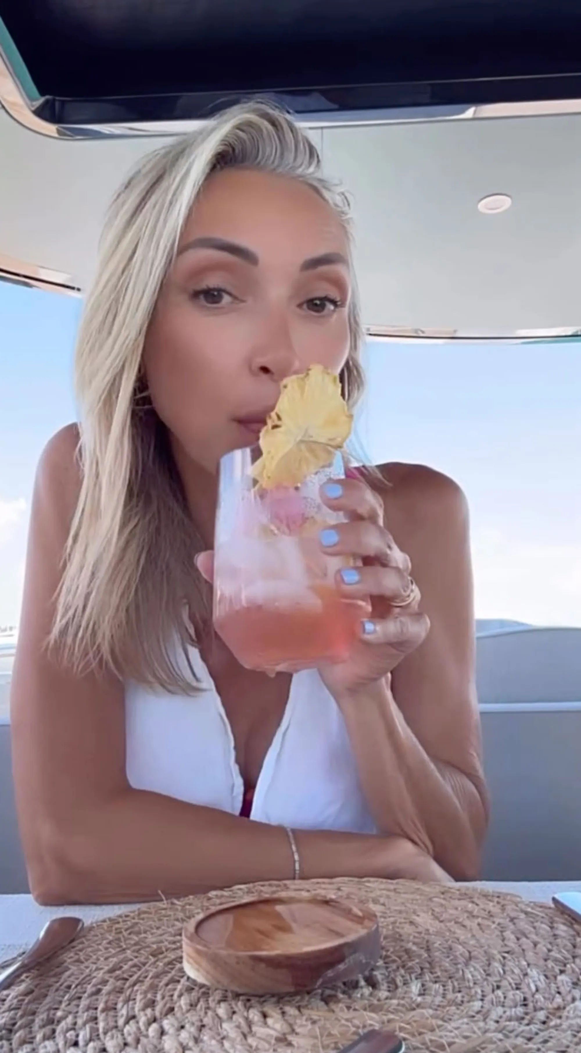Giuliana Rancic sipping a pink drink garnished with pineapple on a boat.