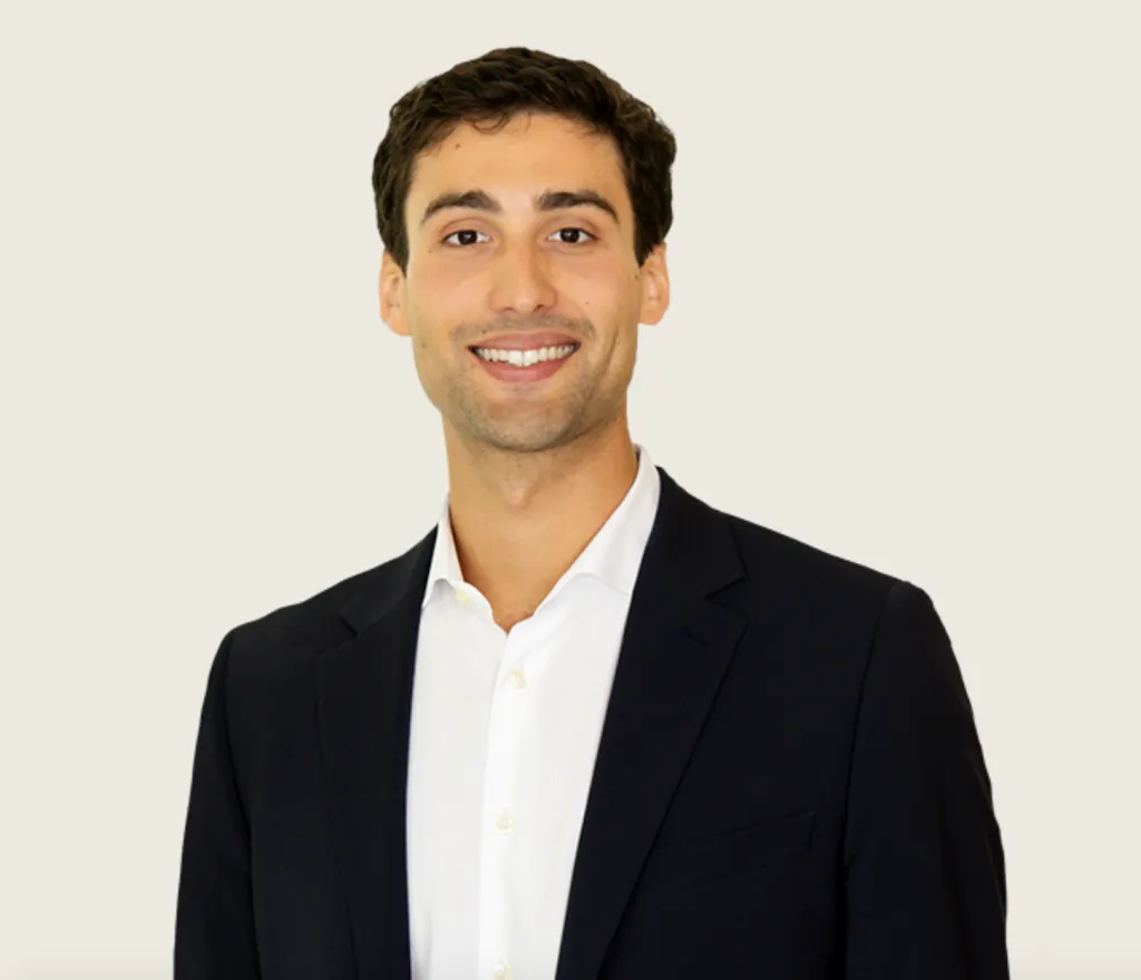 Julian Croonenberghs smiling in a black suit jacket and white shirt.